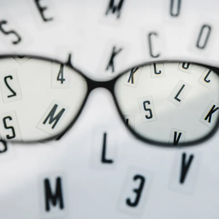Blick durch eine Brille auf unscharfe Buchtsaben beim Augenarzt