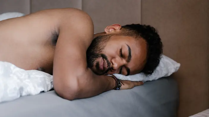junger Mann liegt im Bett und schläft