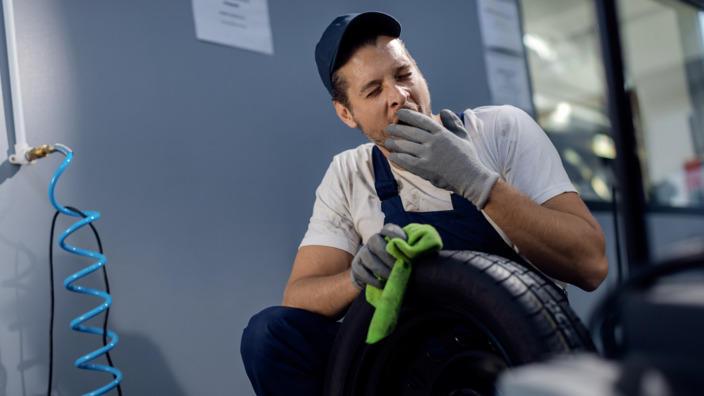 Handwerker in Autowerkstatt gähnt. 