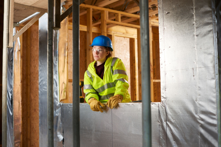 Junge Auszubildene im Handwerk guckt nachdenklich