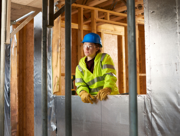 Junge Auszubildende im Handwerk guckt nachdenklich