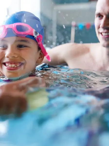 Kind lernt mit Vater schwimmen in der Schwimmhalle
