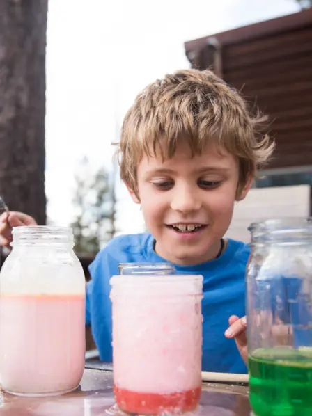 Junge experimentiert im Garten mit Flüssigkeiten