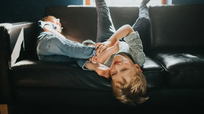 Ein kleiner Junge tobt auf dem Sofa herum