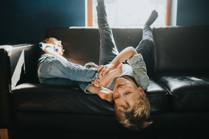 Ist Bewegungsdrang ein Zeichen von ADHS? Zwei Kinder toben auf dem Sofa.