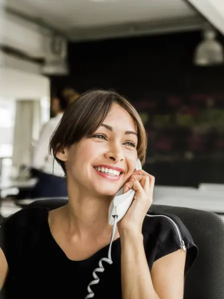 Mitarbeiterin sitzt im Büro und führt ein Kundengespräch am Telefon