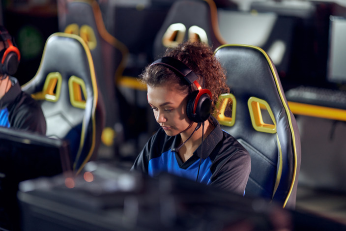 Junge Frau sitzt bei einem Gaming Wettbewerb und spielt