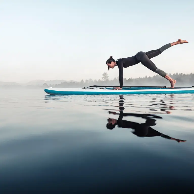 Frau macht Gymnastik-Pose auf einem Surfbrett auf dem Wasser