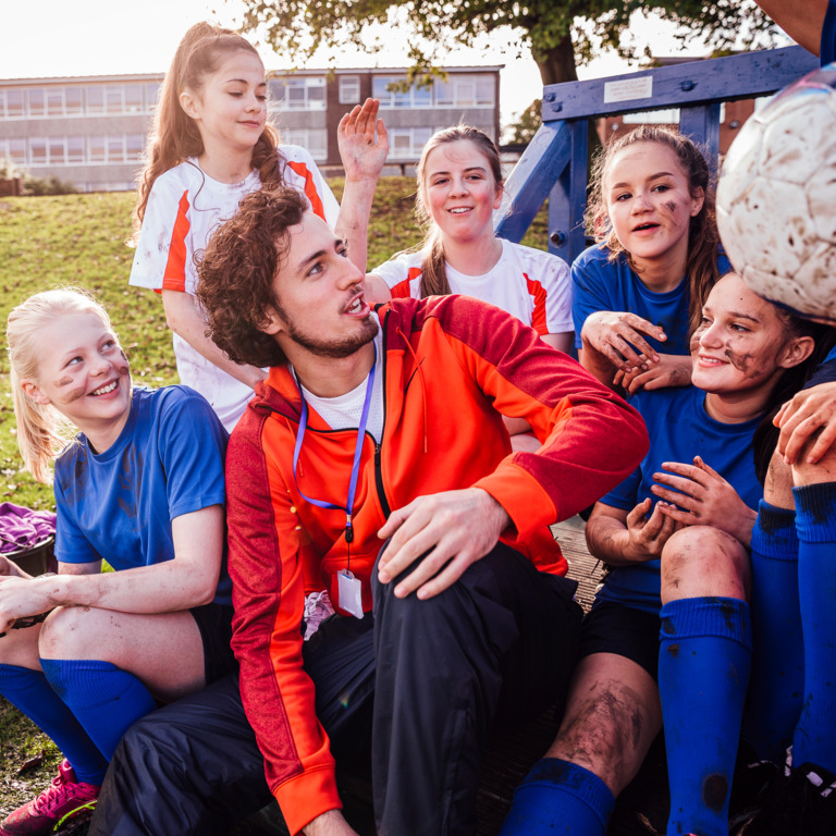 Junger Erwachsener voluntiert und trainiert eine junge Mädchenmannschaft