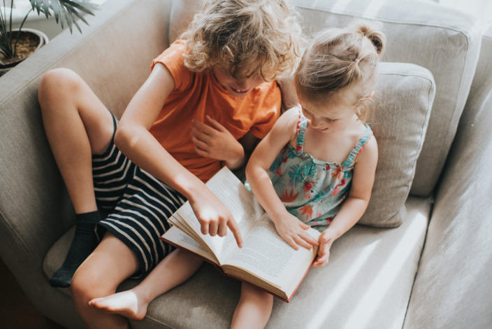 Bücher prägen unsere Sicht auf die Welt: Geschwisterpaar liest gemeinsam in einem Buch.