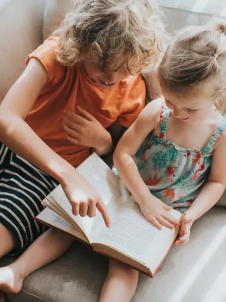 Bücher prägen unsere Sicht auf die Welt: Geschwisterpaar liest gemeinsam in einem Buch.
