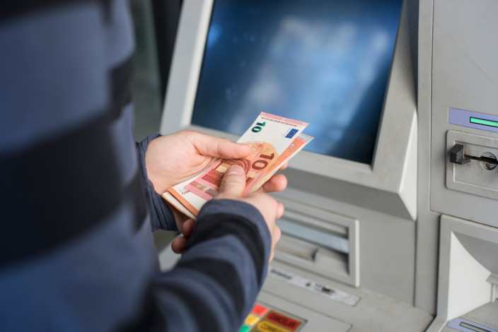 Person hebt Geld vom Automaten ab.