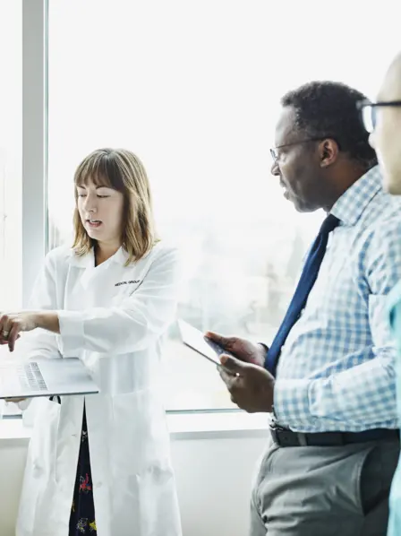 Drei Krankenhausmitarbeiter besprechen etwas am Laptop