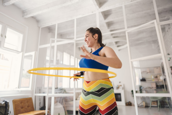 junge Frau liegt ganz im Trend und treibt Sport mit einem Hula-Hoop-Reifen