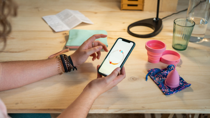 Frau benutzt eine Zyklus-App auf ihrem Handy 