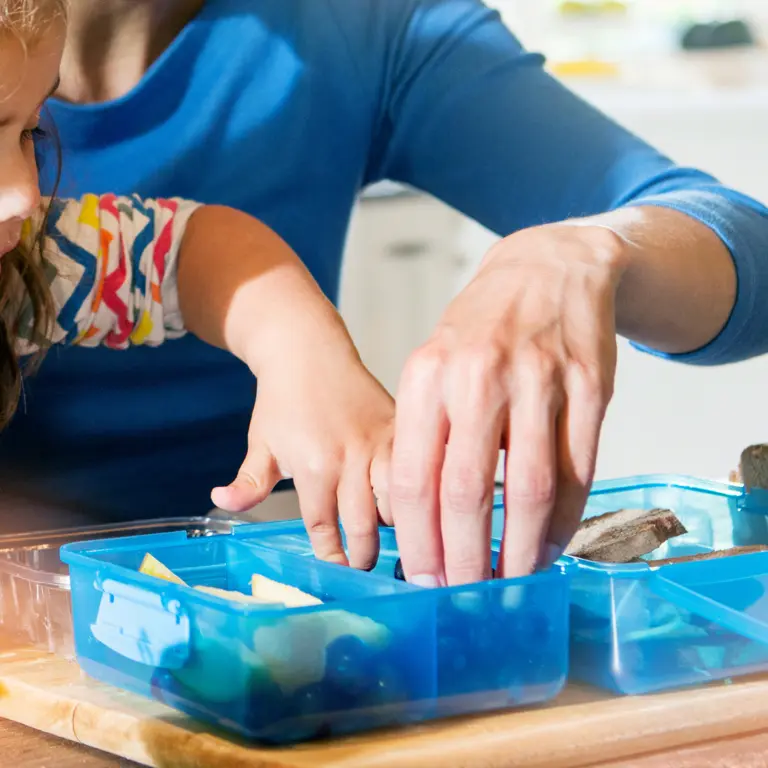 Kindergarten-Kind befüllt gemeinsam mit seiner Mutter eine Proviant-Box