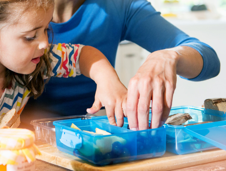 Kindergarten-Kind befüllt gemeinsam mit seiner Mutter eine Proviant-Box