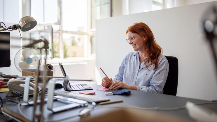 Frau glücklich im Büro am Schreibtisch