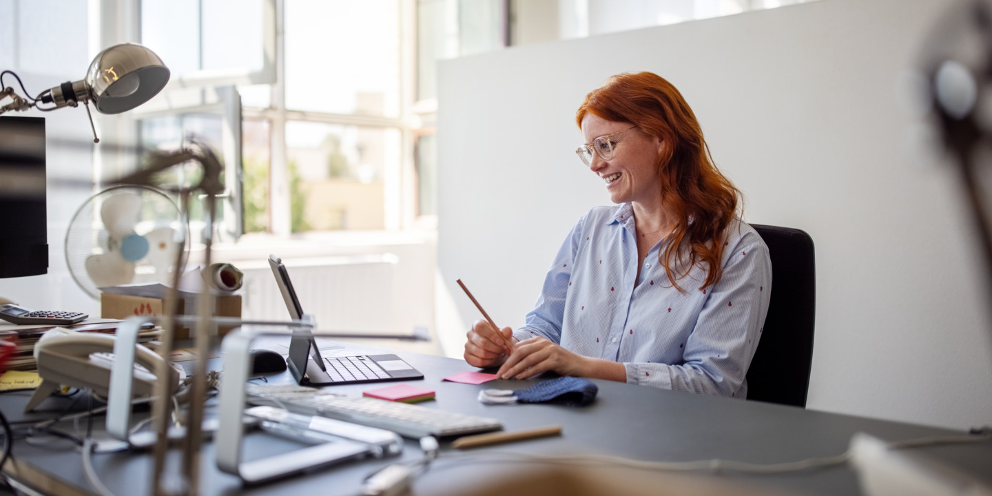 Frau glücklich im Büro am Schreibtisch