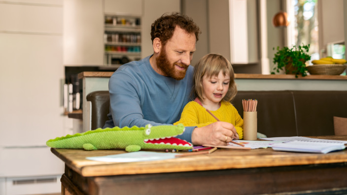 Vater malt mit seiner Tochter am Küchentisch