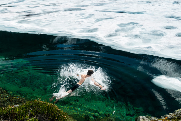 Person schwimmt in einem winterlichen See