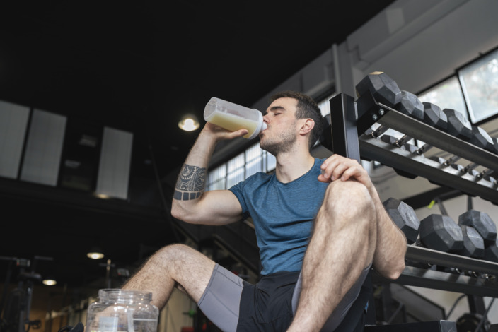 Mann in Sportkleidung trinkt Proteinshake