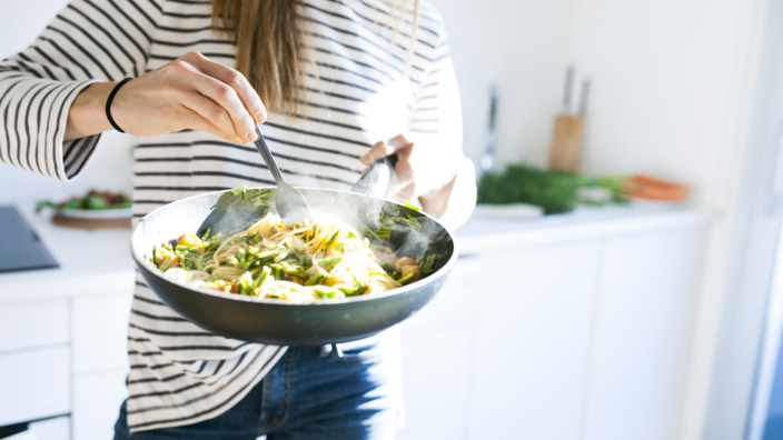 Frau steht mit Schüssel gefüllt mit Pasta in der Küche