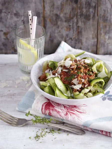 appetitlich in einem tiefen Teller angerichtete Portion Zoodles und ein Glas mit selbstgemachter Zitronenlimonade